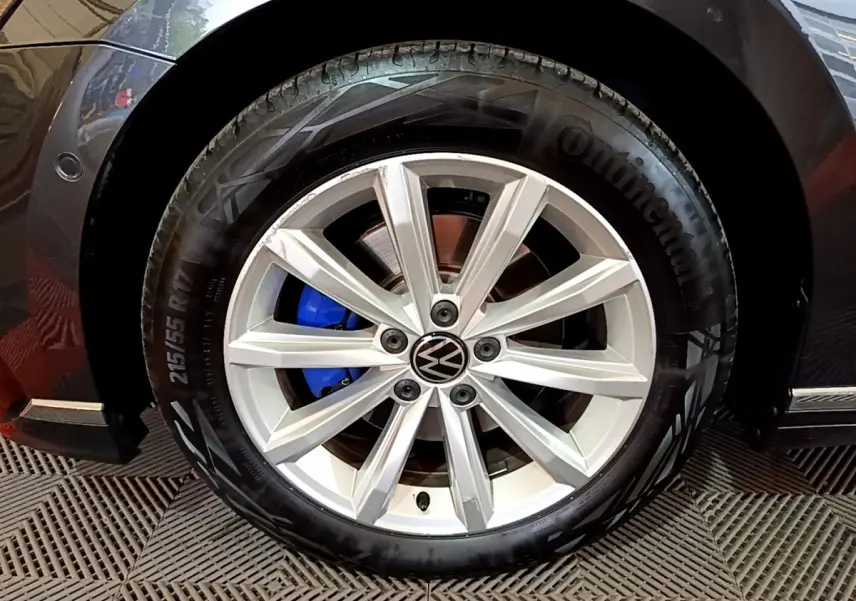 Gros plan sur la roue avant gauche gris foncé d'une Volkswagen Passat GTE avec étrier de frein bleu visible.
