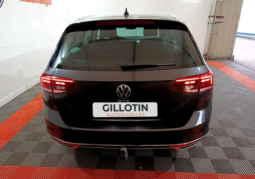 Vue arrière d'une Volkswagen Passat SW GTE hybride rechargeable gris foncé avec feux LED allumés et attelage visible.