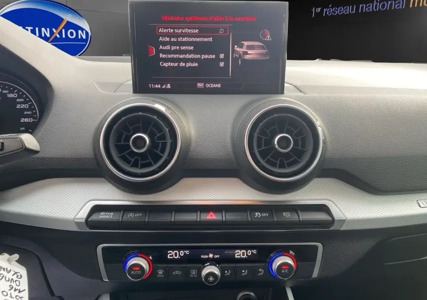 Tableau de bord de l'Audi Q2 30 TDI 2019 avec écran central affichant les aides à la conduite et commandes de climatisation double zone.