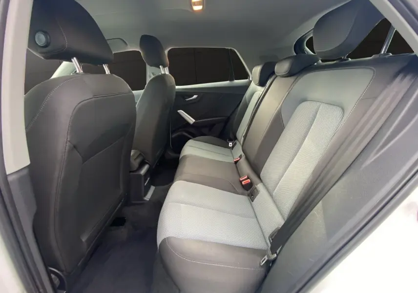 Vue intérieure arrière droite de l'Audi Q2 2019, sièges tissu bicolores gris et noir avec ceintures de sécurité.