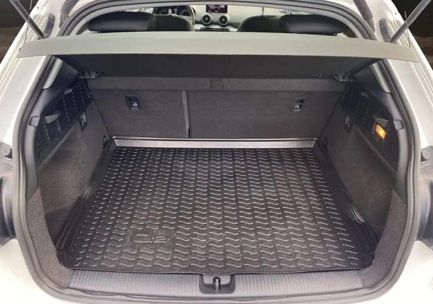 Coffre ouvert d'un Audi Q2 blanc 2019, vue arrière montrant le tapis de coffre noir avec logo Q2.
