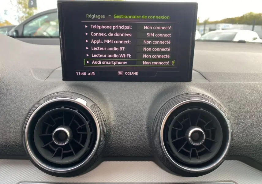 Détail du tableau de bord noir de l'Audi Q2 blanc 2019 avec écran central affichant les connexions non connectées.