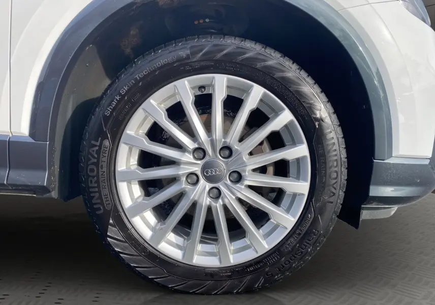 Gros plan sur la roue avant gauche blanche d'un Audi Q2 30 TDI 116 BVM6 avec jante argentée multi-branches.
