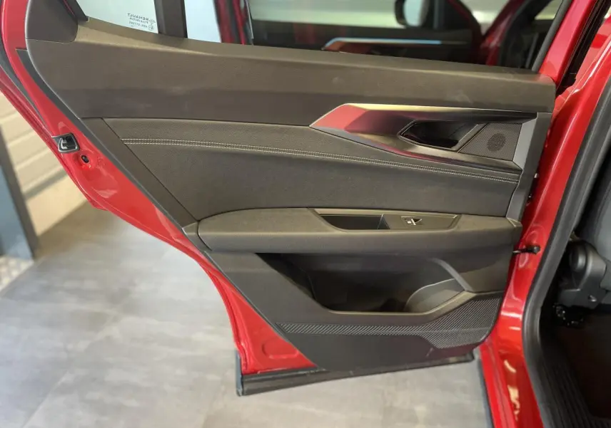 Vue intérieure de la porte arrière gauche rouge du Renault Rafale 2025 avec garniture noire et surpiqûres argentées.