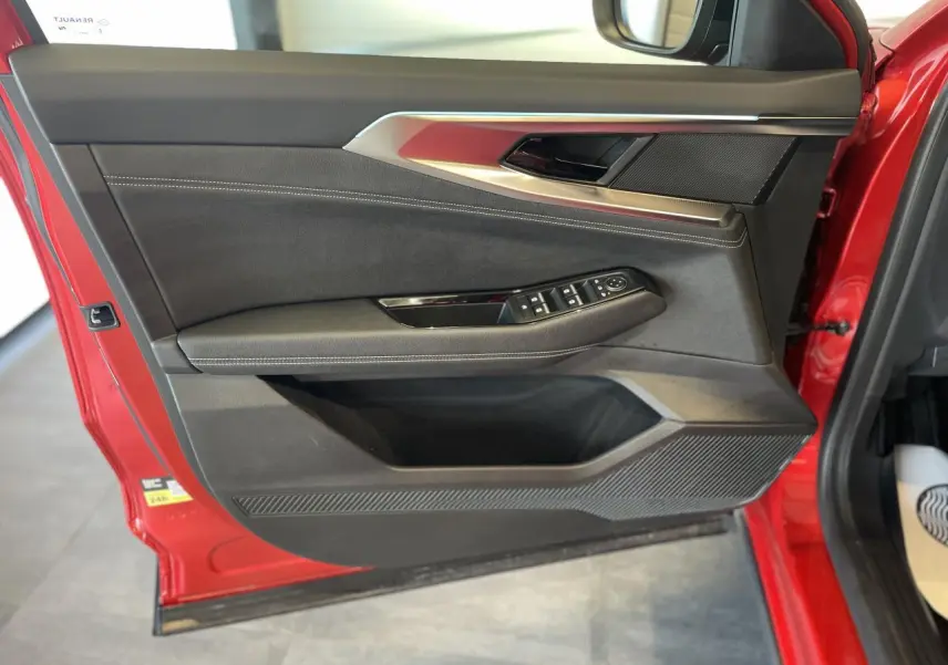 Vue intérieure côté gauche de la porte avant rouge du Renault Rafale 2025 avec commandes de vitres et inserts argentés.