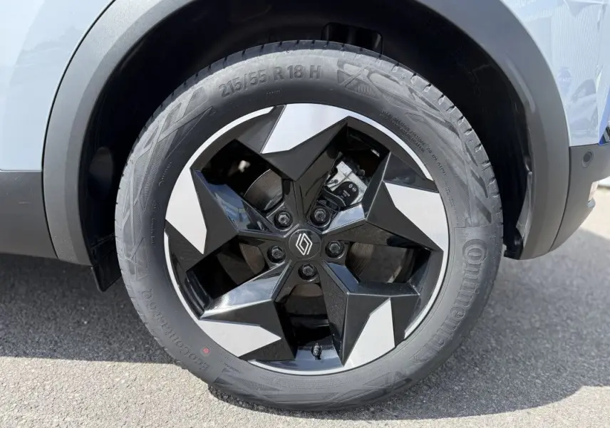 Gros plan sur la roue avant droite du Renault Captur gris Rafale avec jante noire et argentée au design étoilé.