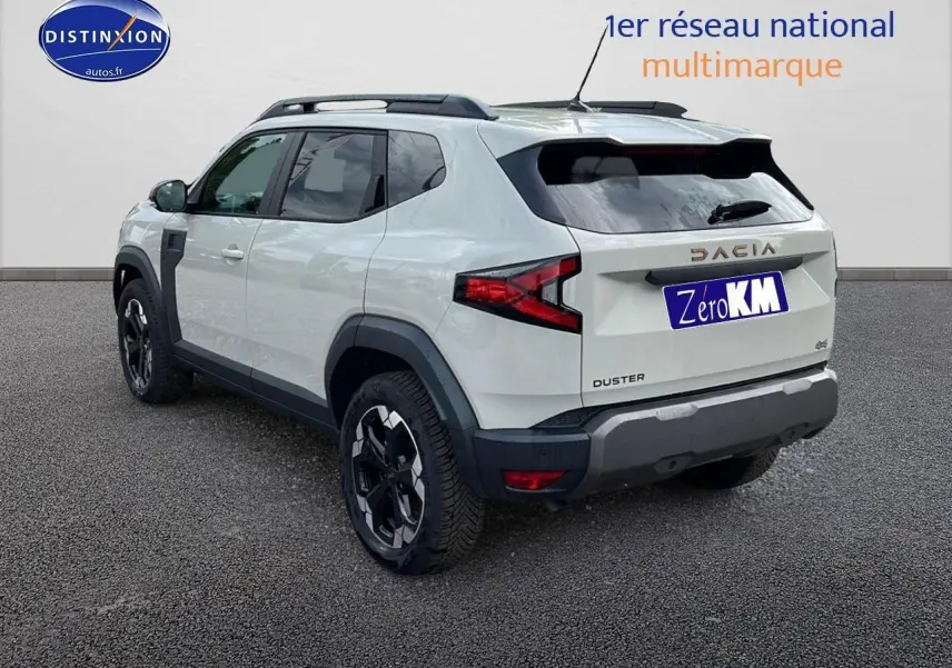 Vue 3/4 arrière droite du Dacia Duster 2025 couleur Sandstone avec barres de toit et jantes noires distinctives.