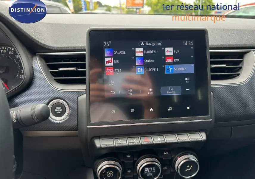 Tableau de bord de Renault Arkana 2022 avec écran tactile central affichant stations radio, boutons de commande et démarrage sans clé.