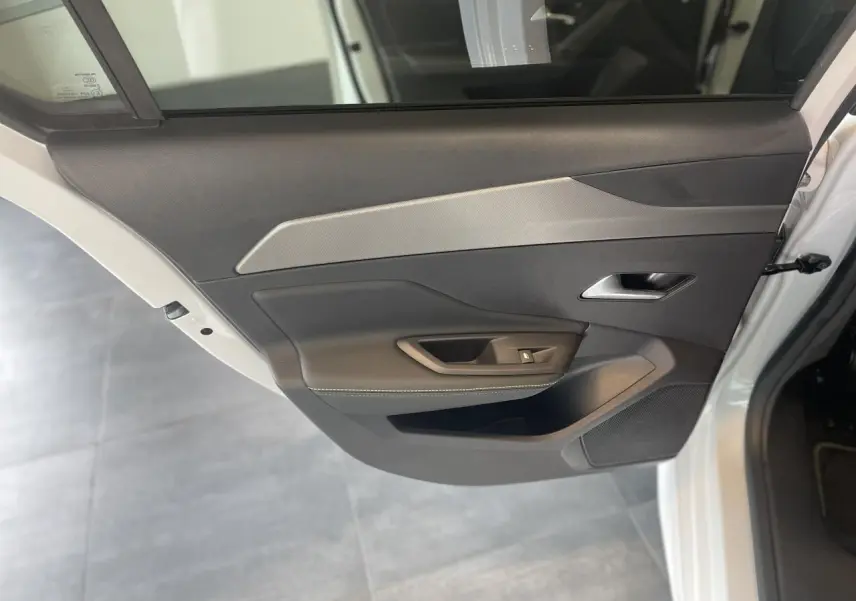 Porte arrière côté droit ouverte d'une Peugeot 308 blanche, avec panneau intérieur noir et insert décoratif gris.