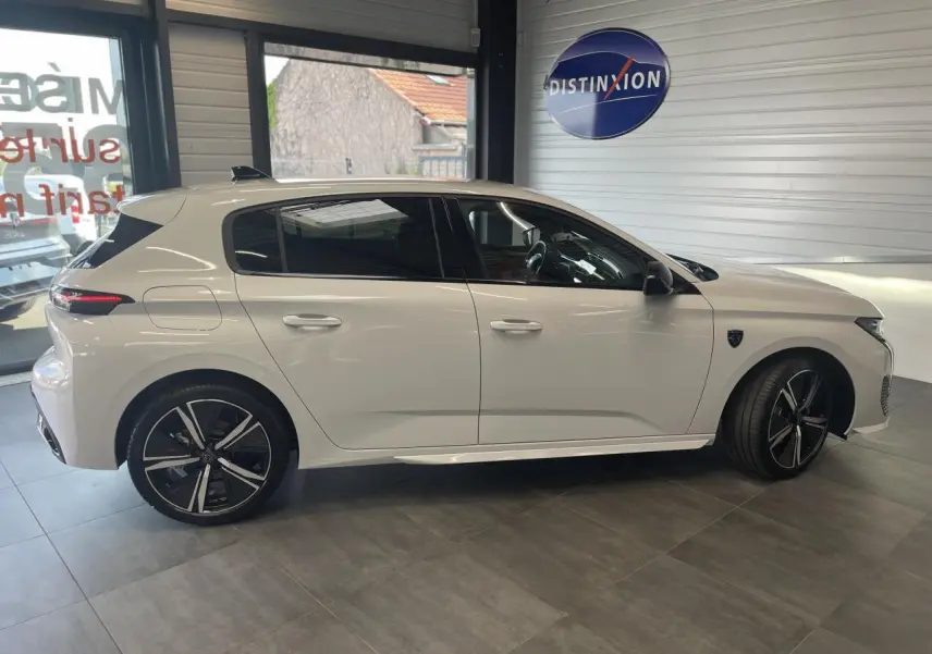 Profil côté gauche d'une Peugeot 308 blanche 2025 en berline GT avec jantes alliage 18'' et toit noir brillant.