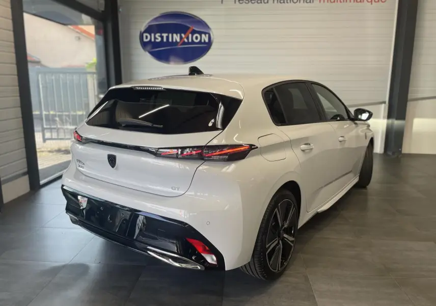 Peugeot 308 GT blanche vue 3/4 arrière droit en intérieur, avec feux arrière LED et jantes alliage noires.