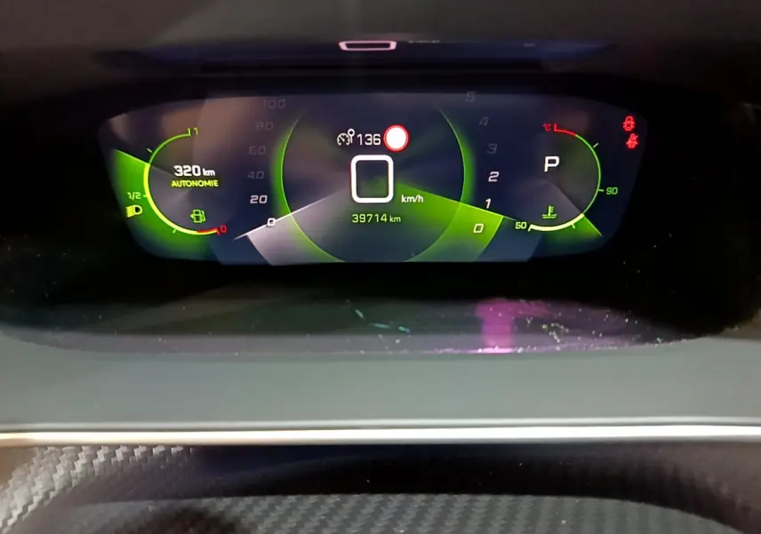 Affichage numérique du tableau de bord de la Peugeot 208 jaune, montrant vitesse zéro et autonomie 320 km.