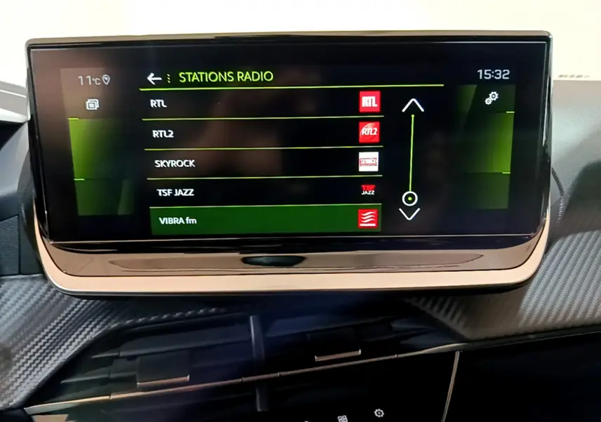 Écran tactile central affichant les stations radio dans l'habitacle d'une Peugeot 208 jaune 2023.