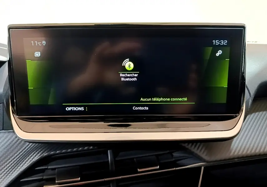 Écran tactile central allumé affichant la recherche Bluetooth dans l'habitacle d'une Peugeot 208 jaune.