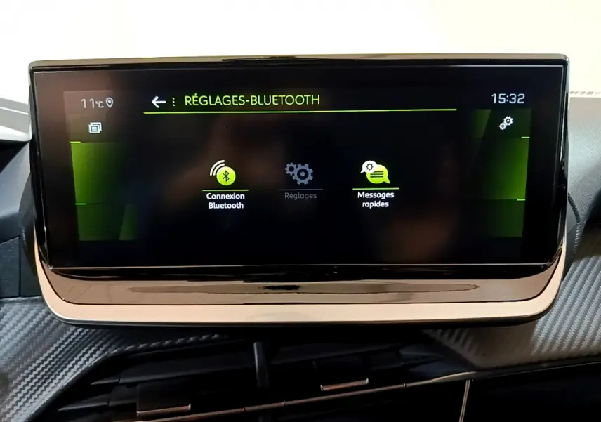 Écran tactile central de la Peugeot 208 jaune 2023 affichant les réglages Bluetooth en intérieur.