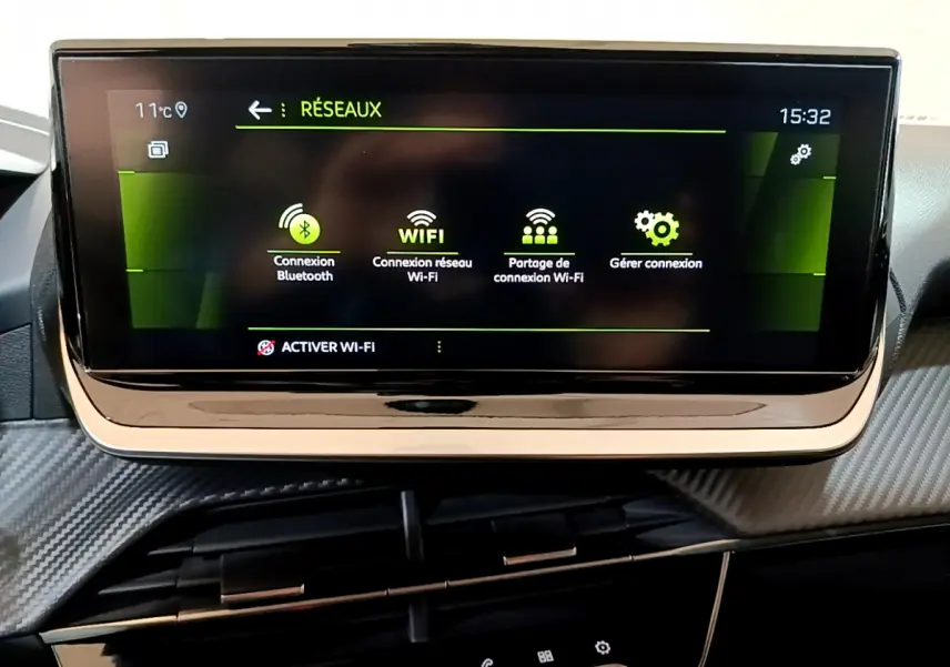 Écran tactile central affichant les options de connexion Bluetooth et Wi-Fi dans l'habitacle d'une Peugeot 208 jaune.