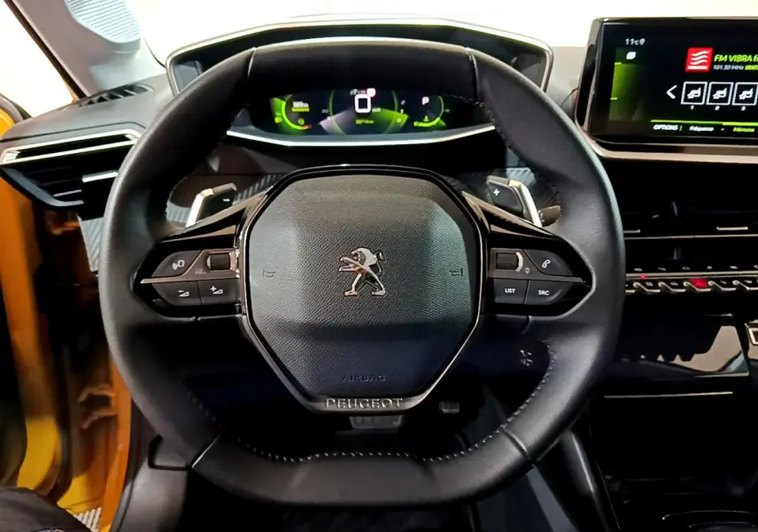 Volant cuir Peugeot 208 jaune 2023 vu de face avec tableau de bord numérique et écran tactile central.