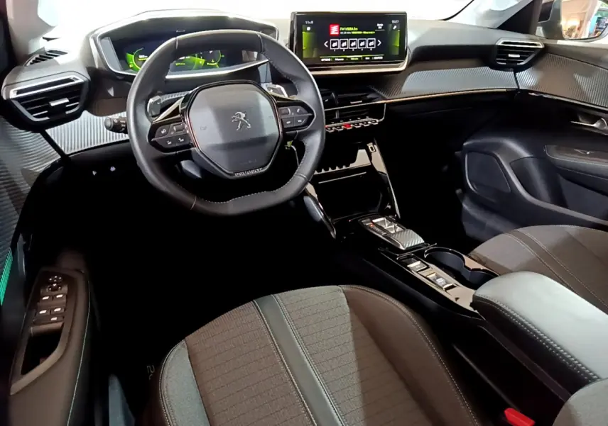 Intérieur de la Peugeot 208 PureTech 100 vue côté conducteur, volant cuir et écran tactile central lumineux.