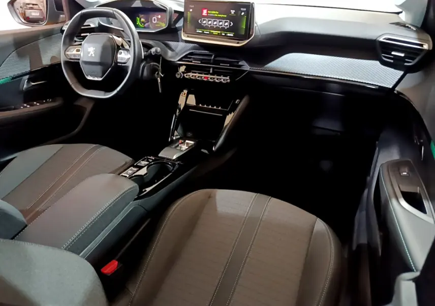 Vue intérieure côté passager avant du tableau de bord et volant cuir de la Peugeot 208 PureTech 100 S&S EAT8 Allure Pack 2023.