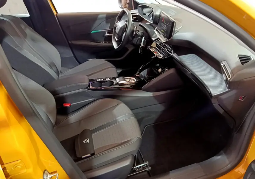 Intérieur avant droit de la Peugeot 208 jaune 2023 avec tableau de bord numérique et sièges gris tissu.