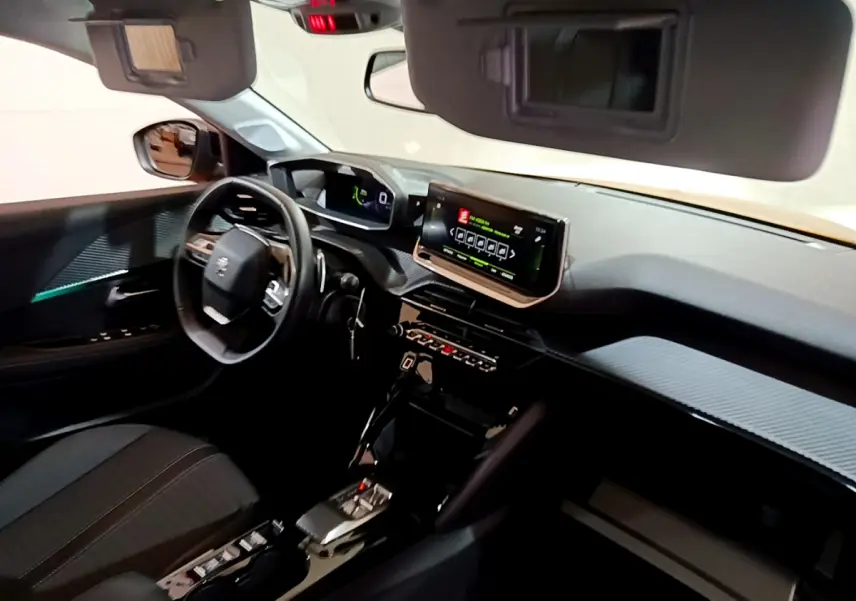 Vue intérieure côté conducteur de la Peugeot 208 jaune 2023, tableau de bord avec écran tactile et volant cuir multifonctions.