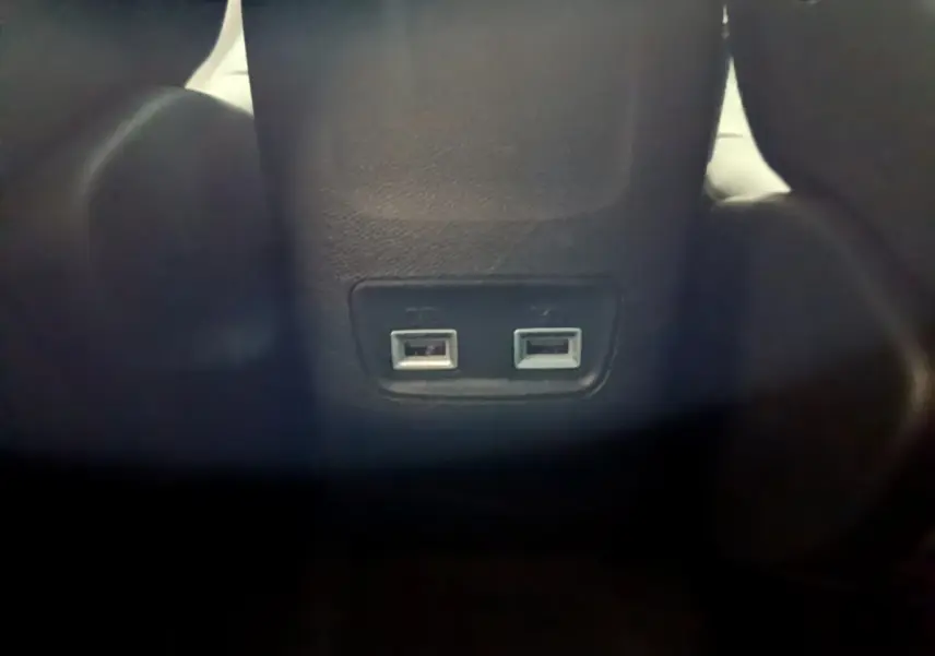 Prise double USB arrière intégrée au dossier central noir de la Peugeot 208 jaune 2023 vue de près