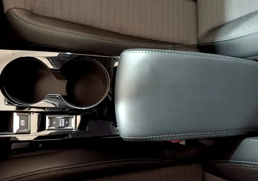 Gros plan sur la console centrale noire avec accoudoir cuir et commandes Drive Mode de la Peugeot 208 jaune 2023.
