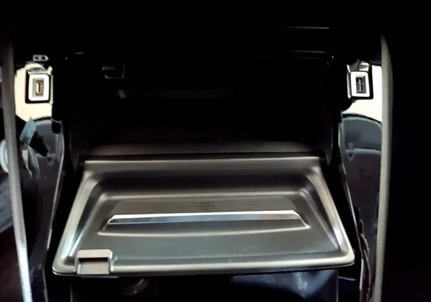 Gros plan sur la boîte à gants ouverte de la Peugeot 208 jaune, montrant son intérieur noir et sa finition sobre.