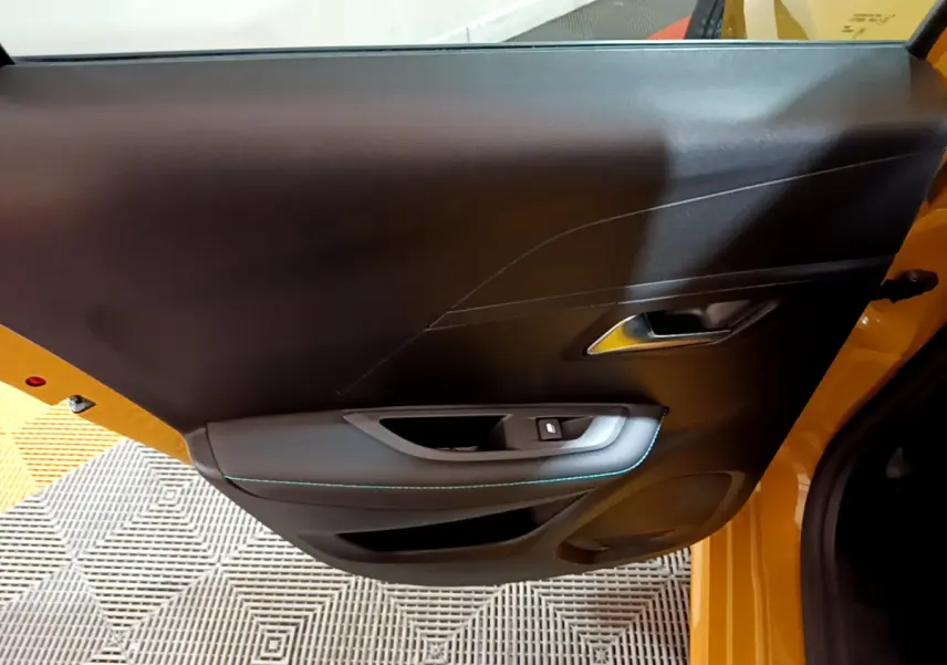 Vue intérieure sur la porte avant gauche noire avec surpiqûres bleues d'une Peugeot 208 jaune 2023 Allure Pack
