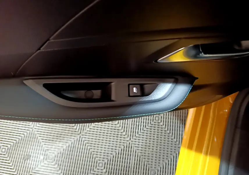 Poignée intérieure côté gauche avec bouton de verrouillage sur porte jaune vif d'une Peugeot 208 2023.