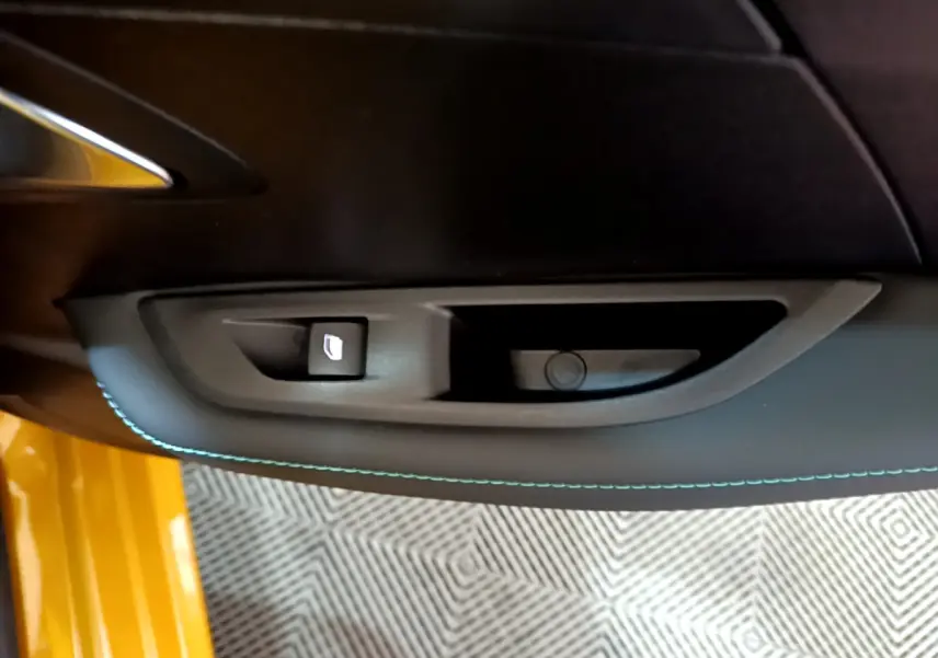 Détail de la commande de lève-vitre côté gauche sur la porte intérieure noire avec surpiqûres bleues d'une Peugeot 208 jaune 2023