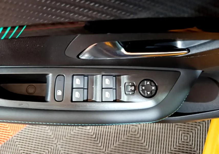 Gros plan sur la commande des vitres et rétroviseurs côté conducteur de la Peugeot 208 jaune 2023.