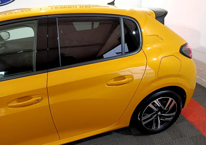 Profil arrière droit d'une Peugeot 208 jaune 2023 avec jantes alliage et vitres teintées.