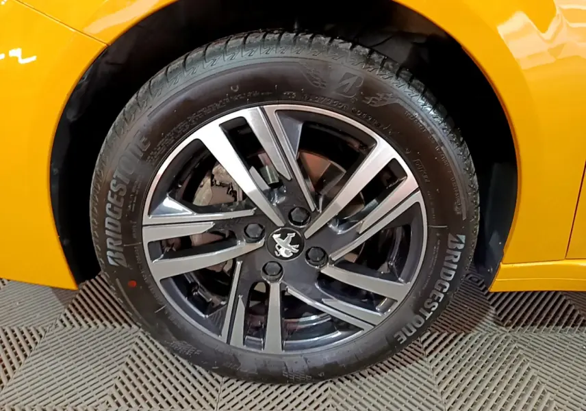Gros plan sur la roue avant gauche de la Peugeot 208 jaune avec jante alliage et pneu Bridgestone.