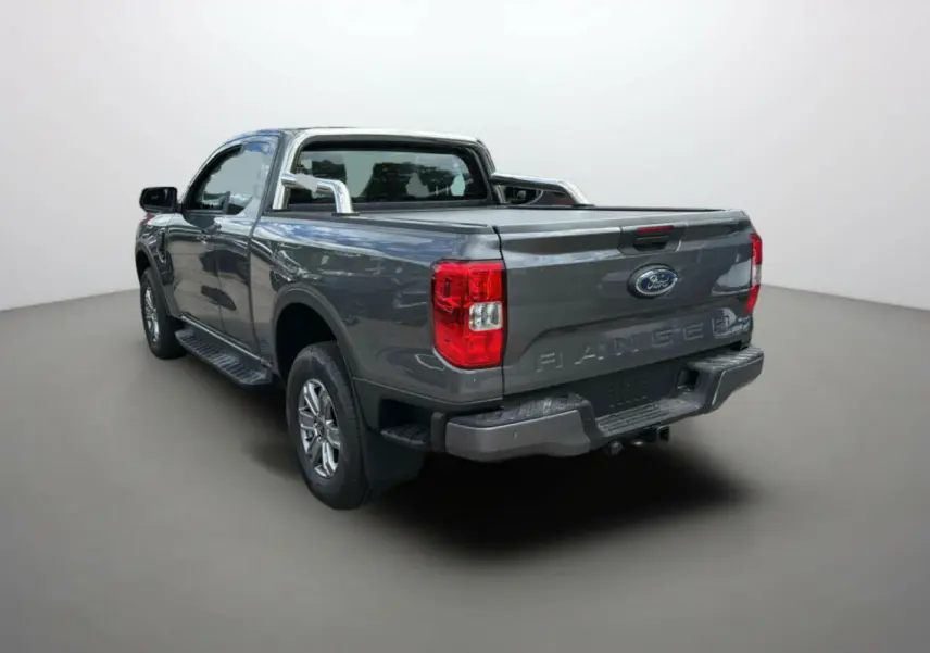 Ford Ranger gris carbone 2025 en vue 3/4 arrière droit avec rideau de benne et barres chromées.