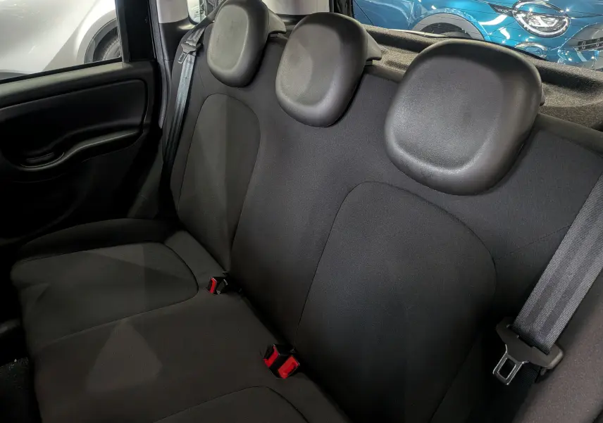 Vue intérieure des sièges arrière en tissu noir de la Fiat Panda 1.0 Hybrid City 2025 avec ceintures de sécurité visibles.
