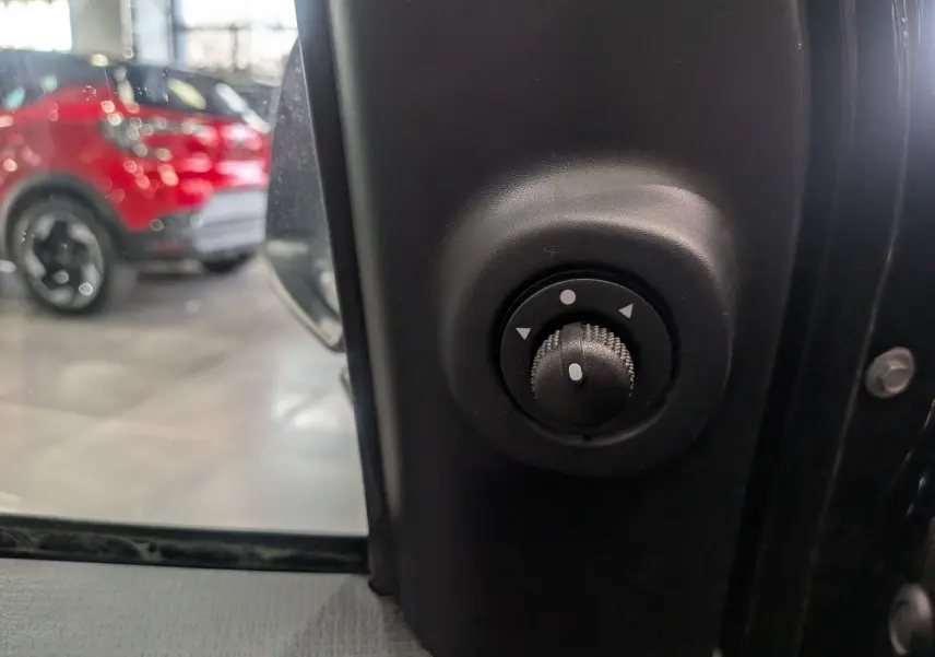 Gros plan sur le réglage électrique des rétroviseurs côté conducteur de la Fiat Panda 1.0 70 CH Hybrid City noir cinéma 2025.