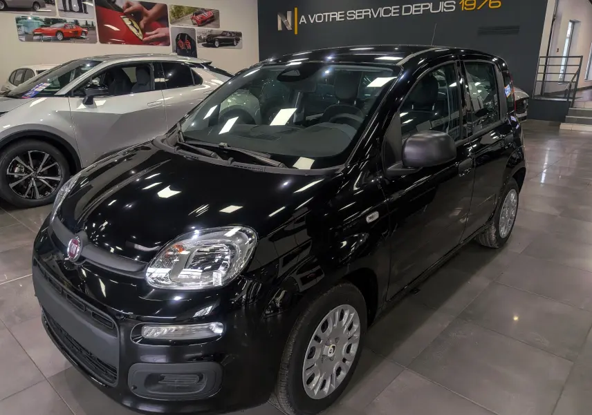 Vue 3/4 avant droite d'une Fiat Panda 1.0 70 CH Hybrid City noire, en showroom avec jantes acier et rétroviseurs noirs.