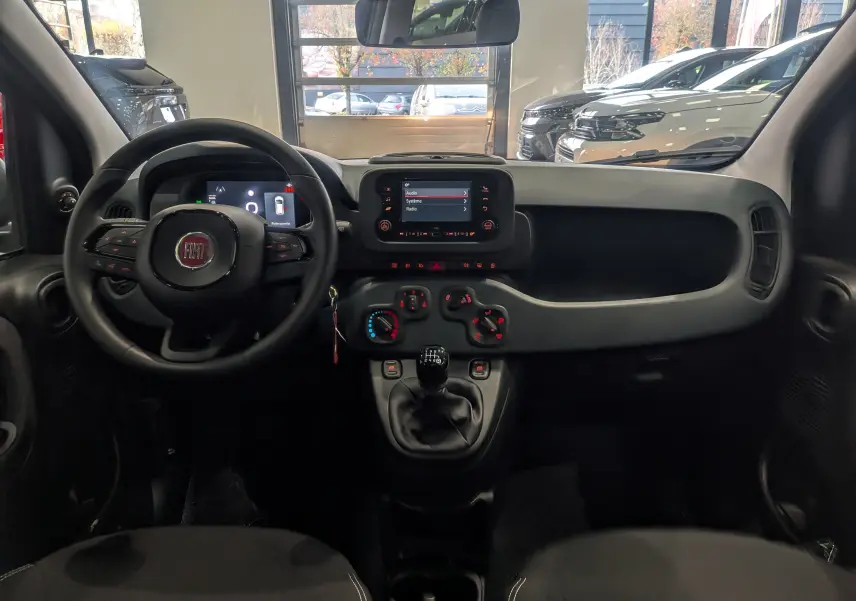 Intérieur de la Fiat Panda 2025 noir Cinéma, vue frontale du tableau de bord avec volant, écran tactile et commandes manuelles.