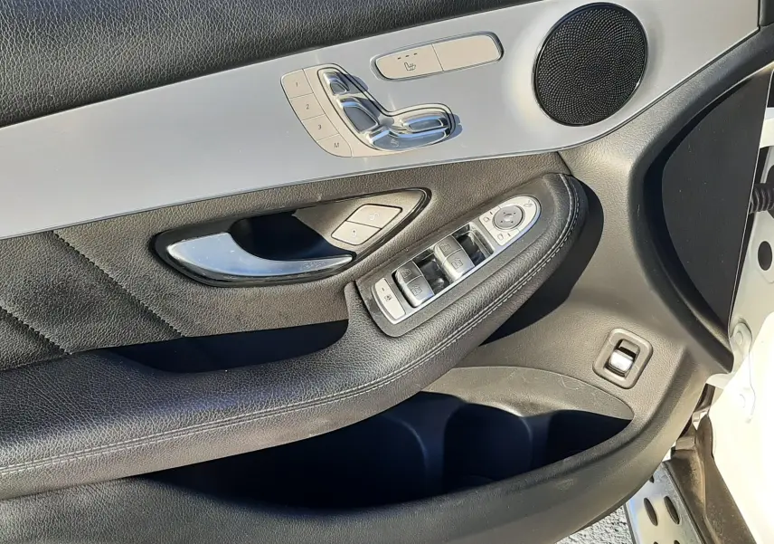 Gros plan sur les commandes de réglage de siège en aluminium brossé et cuir noir dans une Mercedes GLC Coupé blanc.