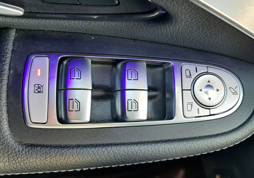 Vue rapprochée de la porte avant gauche blanche d’un Mercedes GLC Coupé 300 AMG Line, avec commandes et haut-parleur visibles.