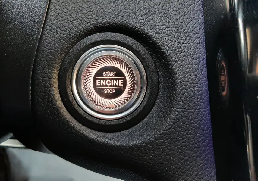 Gros plan sur le levier de vitesses automatique noir à droite du volant d’un Mercedes GLC Coupé blanc, avec bouton start visible.