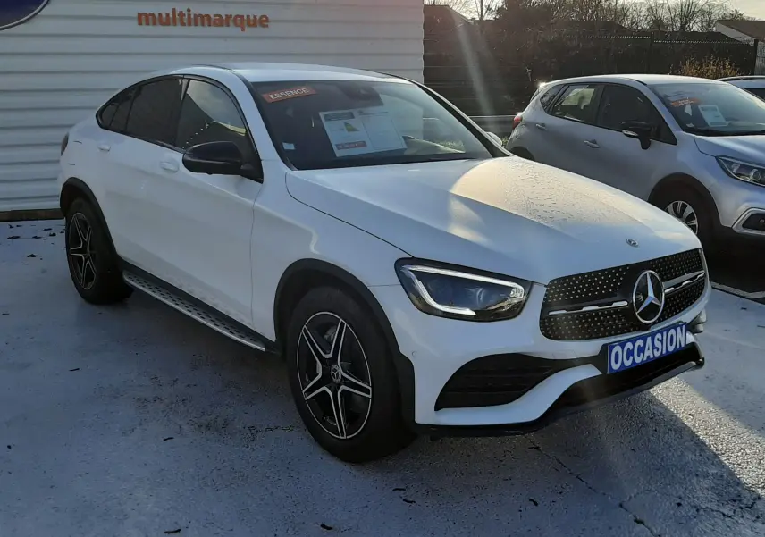 Vue avant d'une Mercedes GLC Coupé 300 4MATIC AMG Line blanche avec calandre noire et plaque "OCCASION".