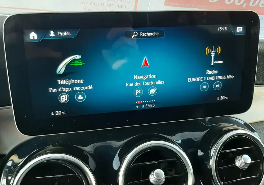 Vue rapprochée du tableau de bord noir brillant de la Mercedes GLC Coupé 300 AMG, avec trois aérateurs ronds chromés et commandes climatisation.