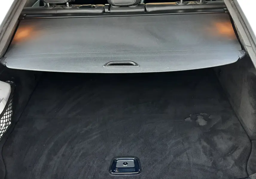 Vue plongeante sur le coffre noir spacieux d’un Mercedes GLC Coupé blanc, avec tapis et seuil en métal visible.