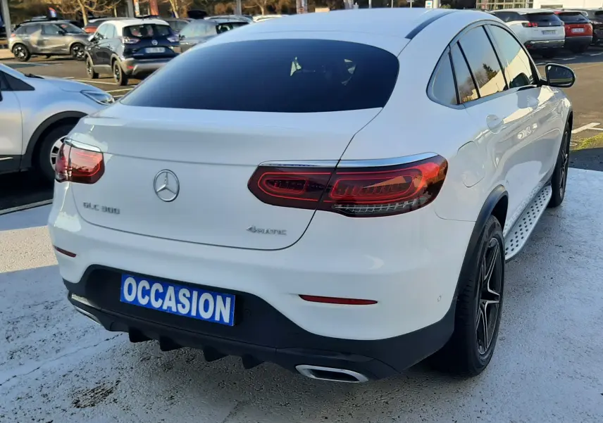 Vue arrière d'un Mercedes GLC 300 4MATIC blanc avec feux LED et plaque "OCCASION" sur parking extérieur.