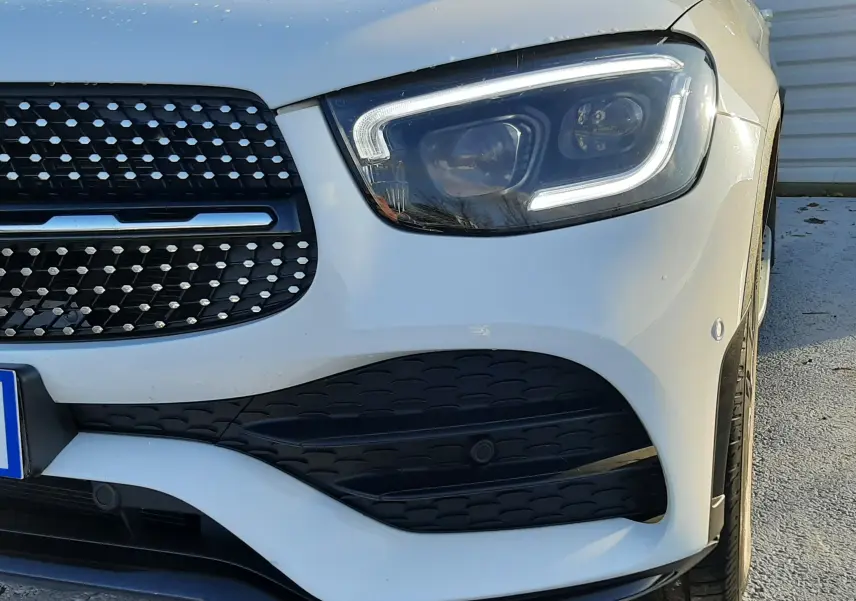 Vue 3/4 avant droit d'un Mercedes GLC Coupé blanc avec rétroviseur noir et vitres teintées.