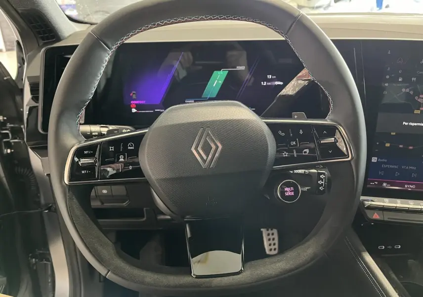 Vue rapprochée du volant noir avec surpiqûres bleues et écran numérique du tableau de bord du Renault Austral hybride 2025.