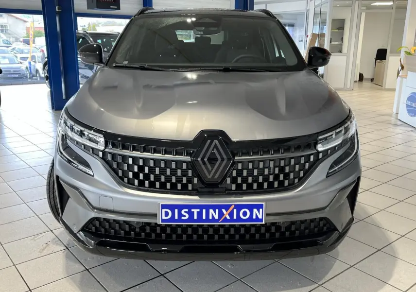 Vue avant d’un Renault Austral gris avec calandre à damier noire et logo Alpine, en showroom intérieur.