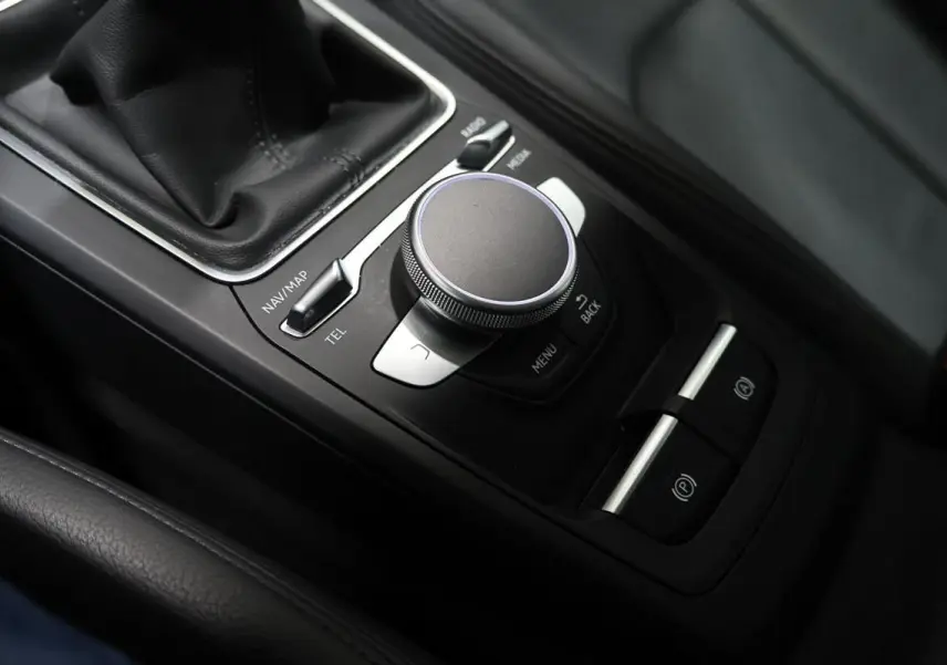 Vue rapprochée de la console centrale noire avec molette de contrôle et levier de vitesse du Audi Q2 gris.